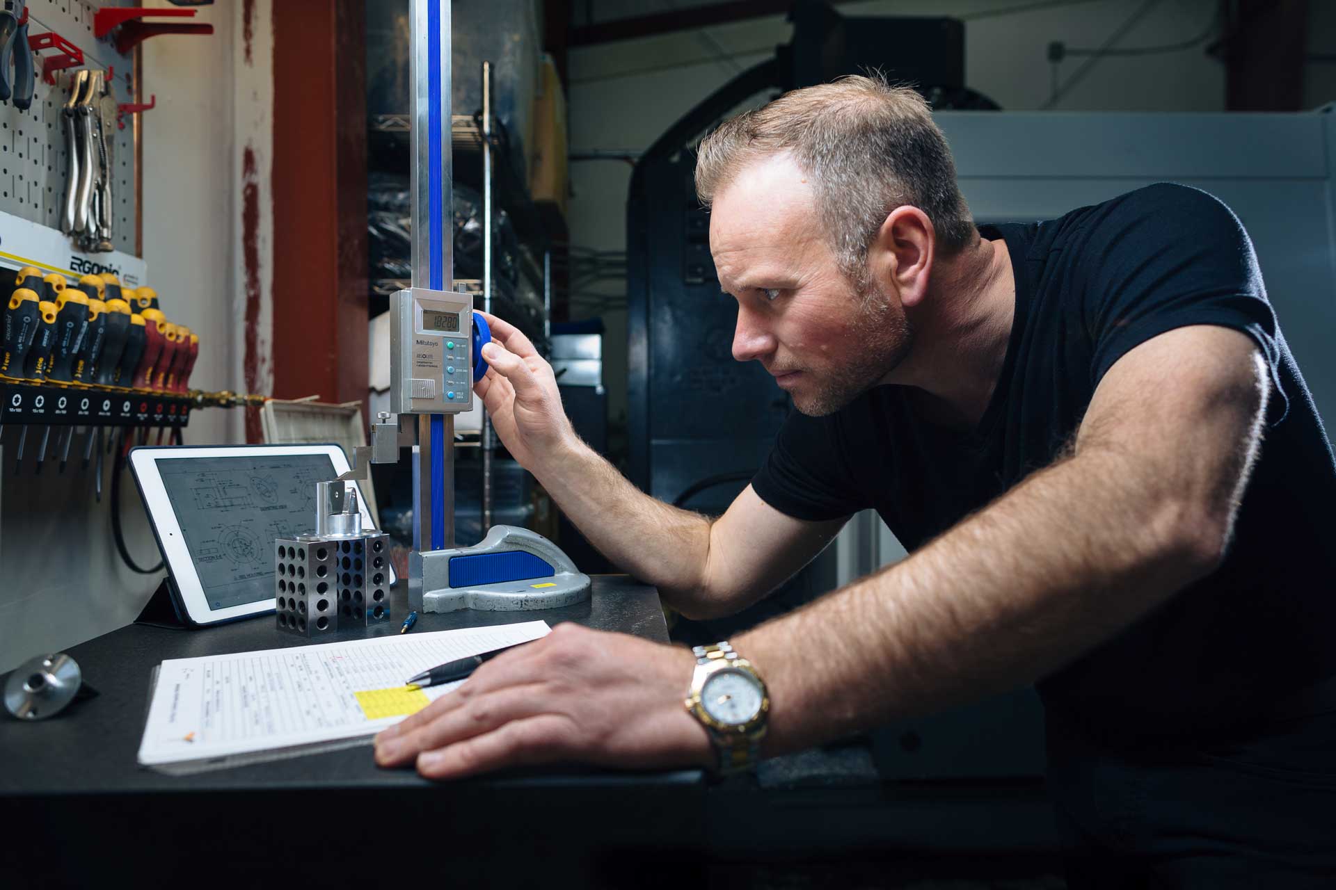 A machinist measuring a finished part with a height gauge at Jarno International